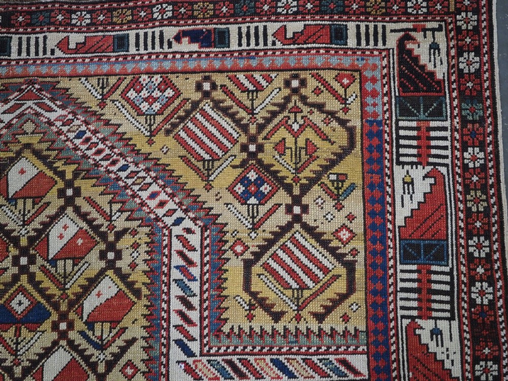 A hand-knotted Caucasian Marasali prayer rug featuring a yellow ground with a prominent pointed mihrab arch, diamond lattice patterns, and geometric borders in red, blue, and brown. View XI