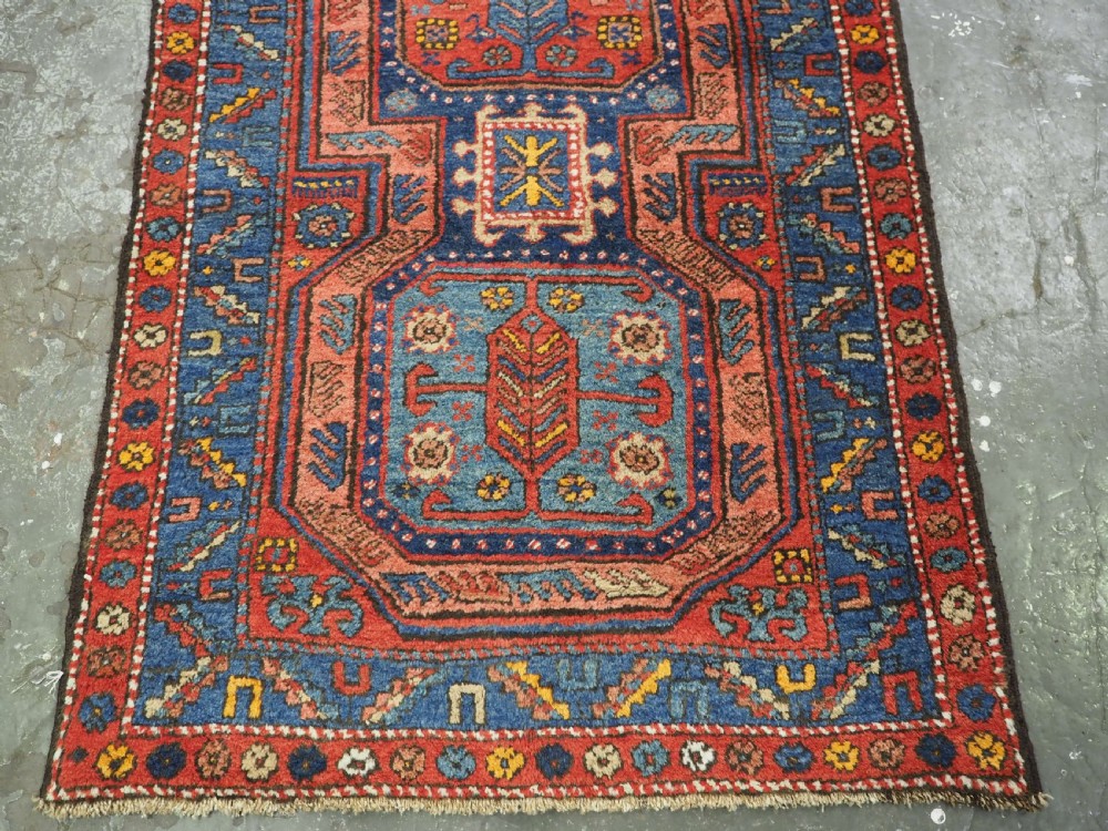 A long hand-knotted wool runner rug featuring geometric garden medallions in indigo blue, terracotta red, and gold within a patterned border. View VIII