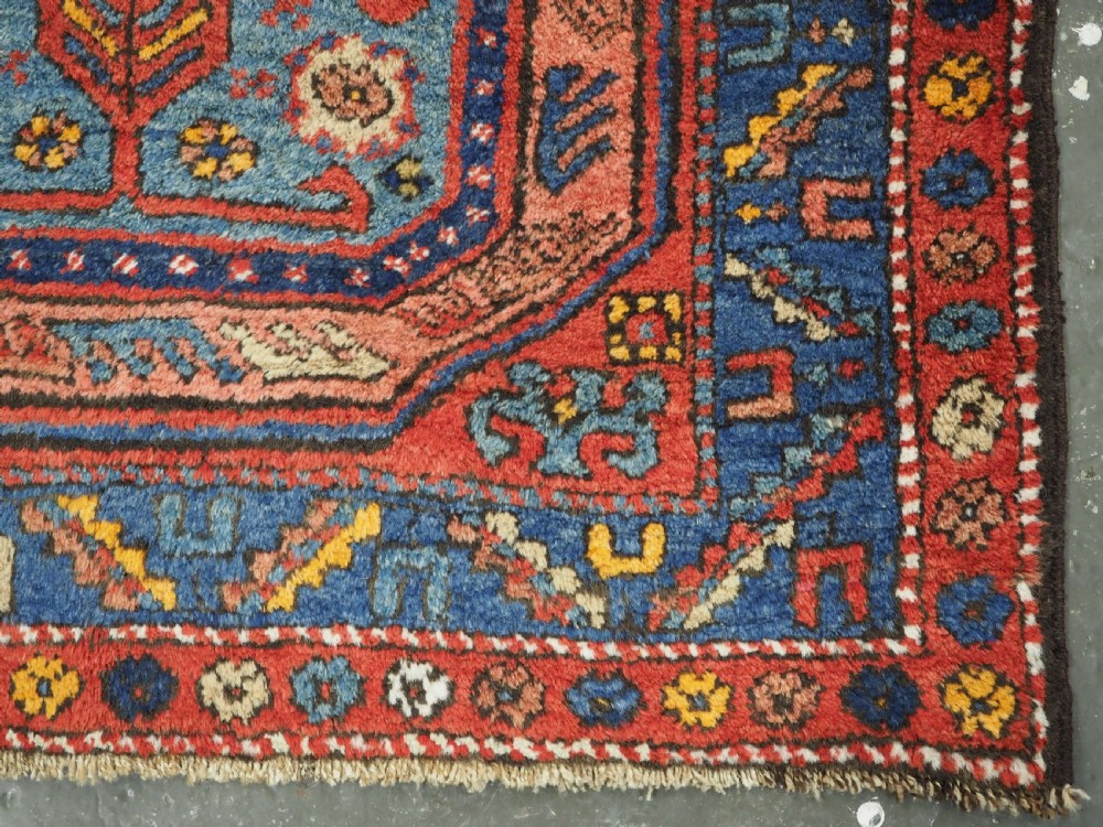 A long hand-knotted wool runner rug featuring geometric garden medallions in indigo blue, terracotta red, and gold within a patterned border. View XIV