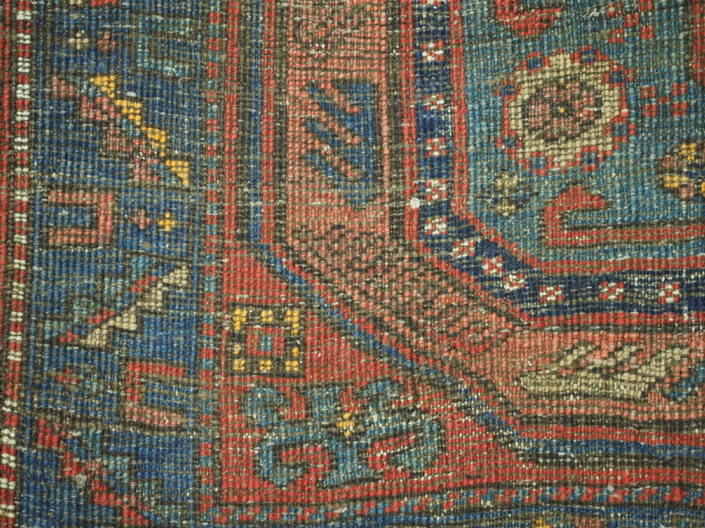 A long hand-knotted wool runner rug featuring geometric garden medallions in indigo blue, terracotta red, and gold within a patterned border. View XV
