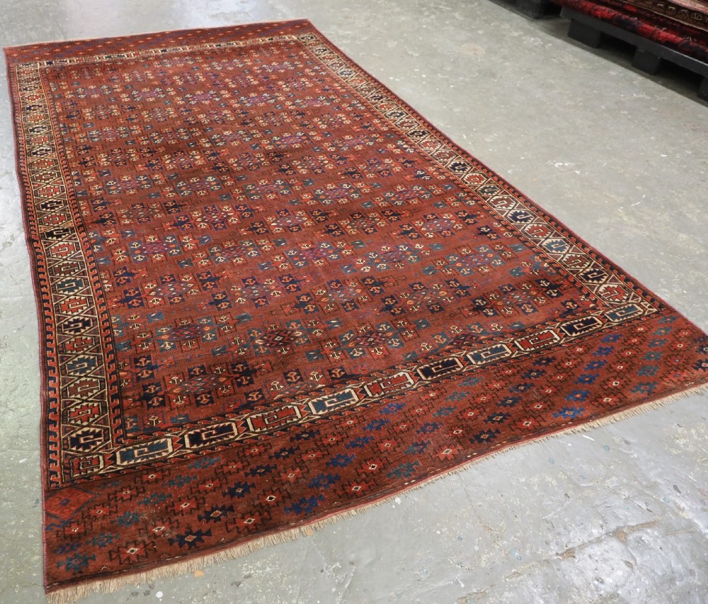 An antique Yomut Turkmen hand-knotted wool carpet featuring repeating Kepse gul geometric diamond patterns in deep red, navy, and cream. View II