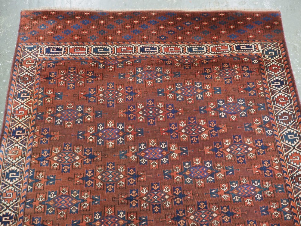 An antique Yomut Turkmen hand-knotted wool carpet featuring repeating Kepse gul geometric diamond patterns in deep red, navy, and cream. View III