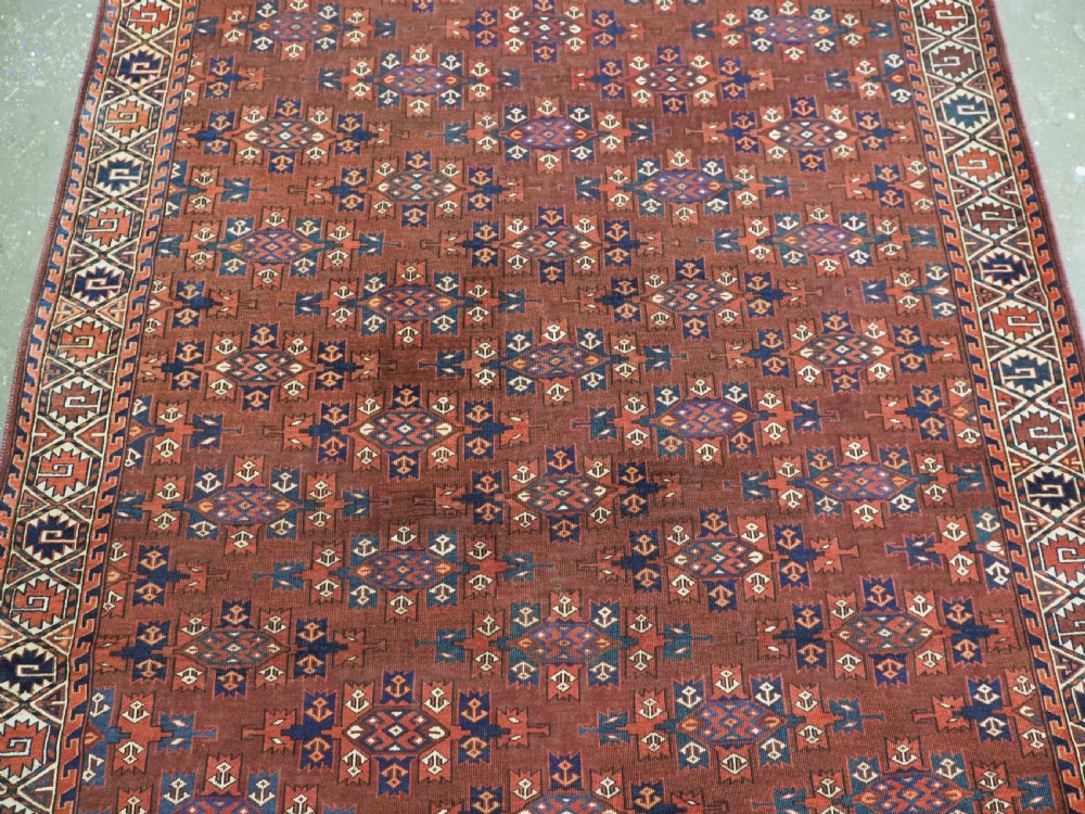 An antique Yomut Turkmen hand-knotted wool carpet featuring repeating Kepse gul geometric diamond patterns in deep red, navy, and cream. View IV