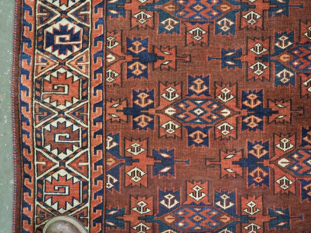 An antique Yomut Turkmen hand-knotted wool carpet featuring repeating Kepse gul geometric diamond patterns in deep red, navy, and cream. View V