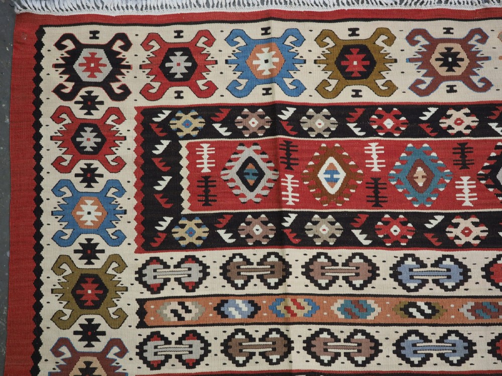 An antique flatweave Pirot Sarkoy wool rug featuring horizontal geometric bands in red, cream, black, and blue. View VI