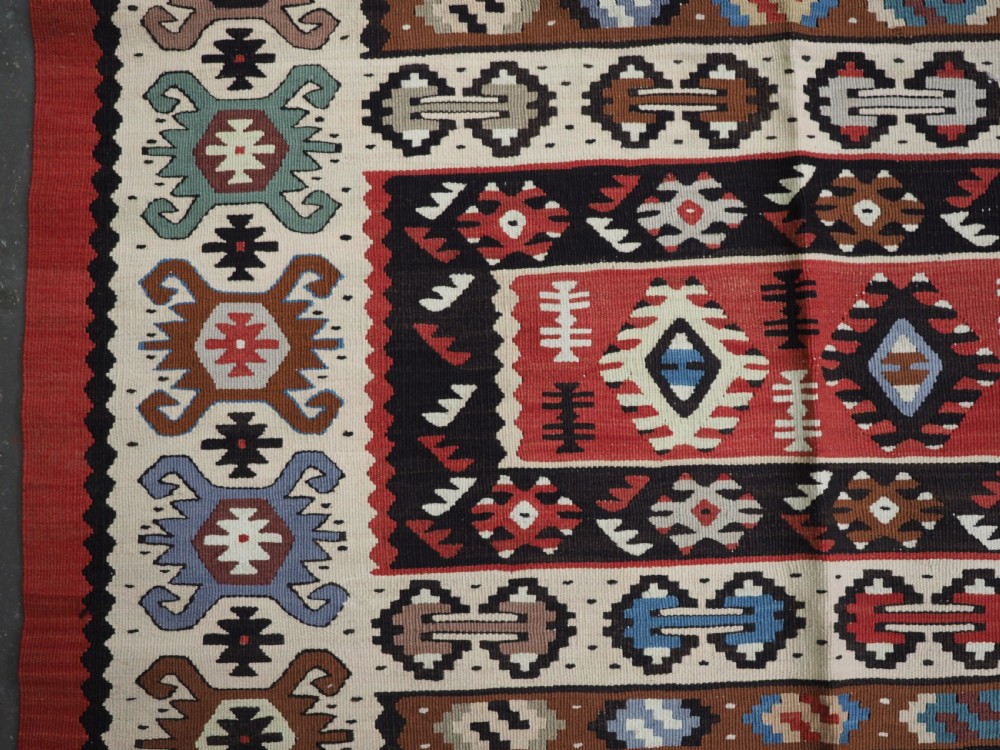 An antique flatweave Pirot Sarkoy wool rug featuring horizontal geometric bands in red, cream, black, and blue. View VII