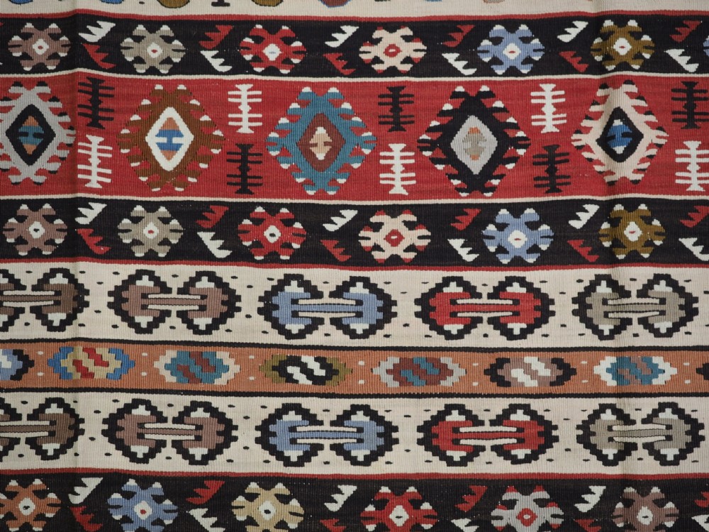 An antique flatweave Pirot Sarkoy wool rug featuring horizontal geometric bands in red, cream, black, and blue. View VIII