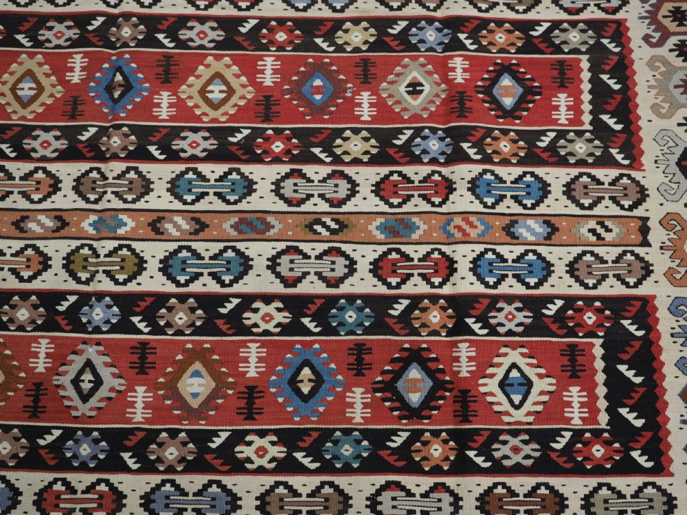 An antique flatweave Pirot Sarkoy wool rug featuring horizontal geometric bands in red, cream, black, and blue. View IX