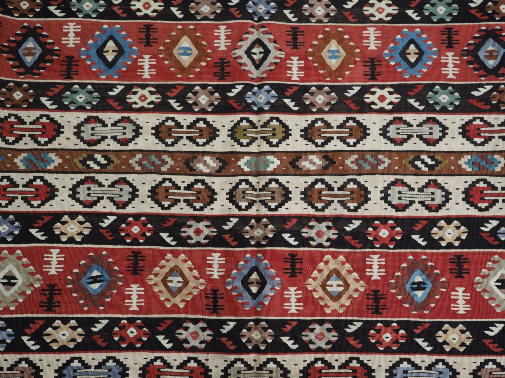 An antique flatweave Pirot Sarkoy wool rug featuring horizontal geometric bands in red, cream, black, and blue. View X