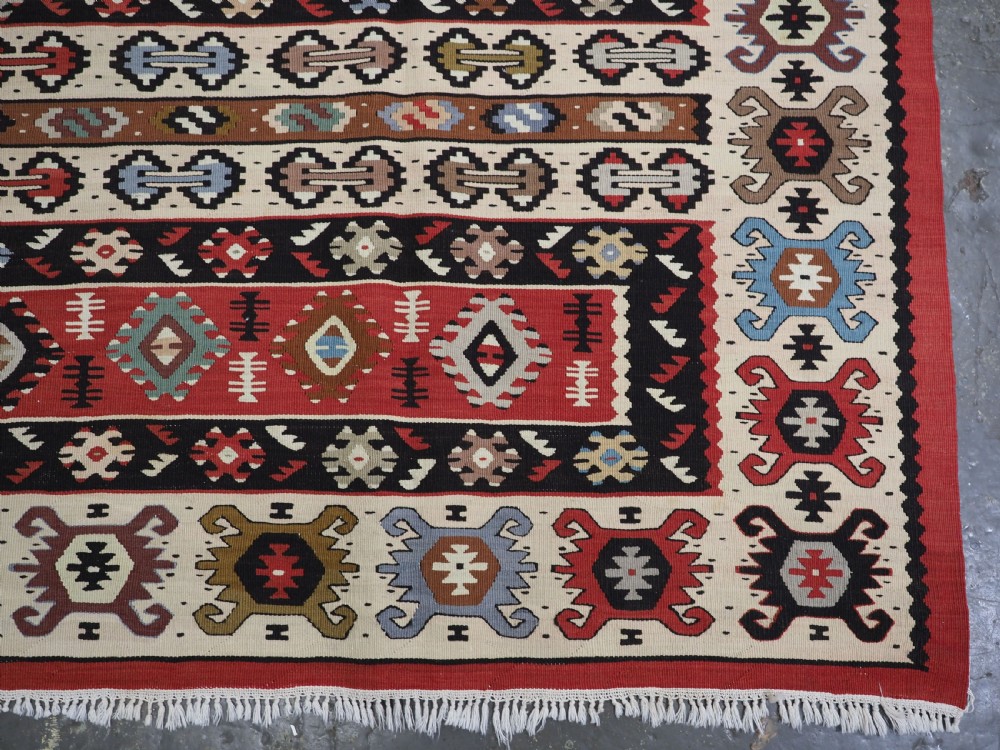 An antique flatweave Pirot Sarkoy wool rug featuring horizontal geometric bands in red, cream, black, and blue. View XI
