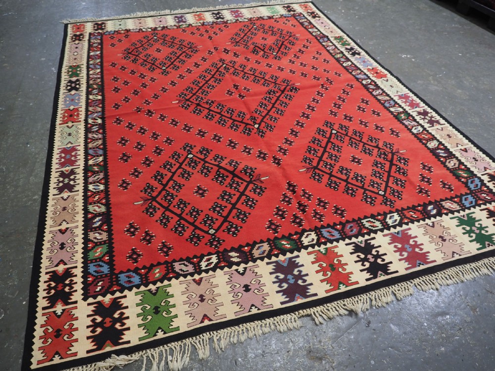 An antique red flat-weave Pirot Sarkoy wool kilim featuring geometric diamond motifs and a multi-coloured decorative border. View II