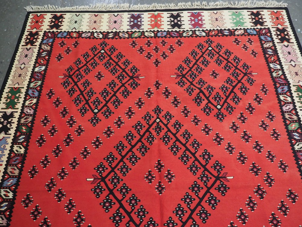 An antique red flat-weave Pirot Sarkoy wool kilim featuring geometric diamond motifs and a multi-coloured decorative border. View III