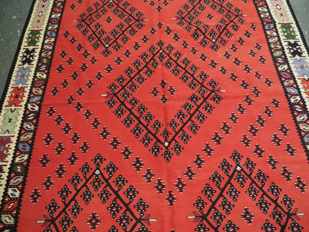 An antique red flat-weave Pirot Sarkoy wool kilim featuring geometric diamond motifs and a multi-coloured decorative border. View IV