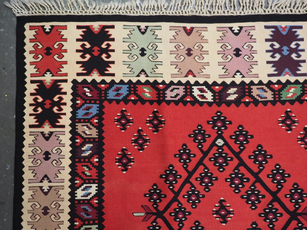 An antique red flat-weave Pirot Sarkoy wool kilim featuring geometric diamond motifs and a multi-coloured decorative border. View VI