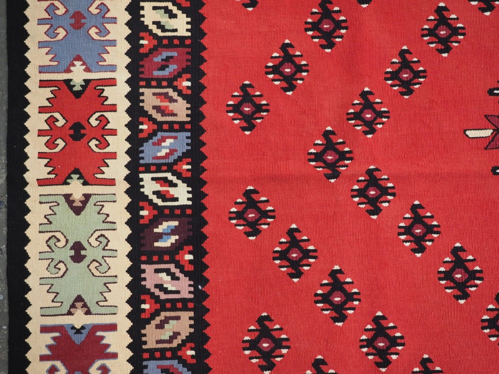 An antique red flat-weave Pirot Sarkoy wool kilim featuring geometric diamond motifs and a multi-coloured decorative border. View VII