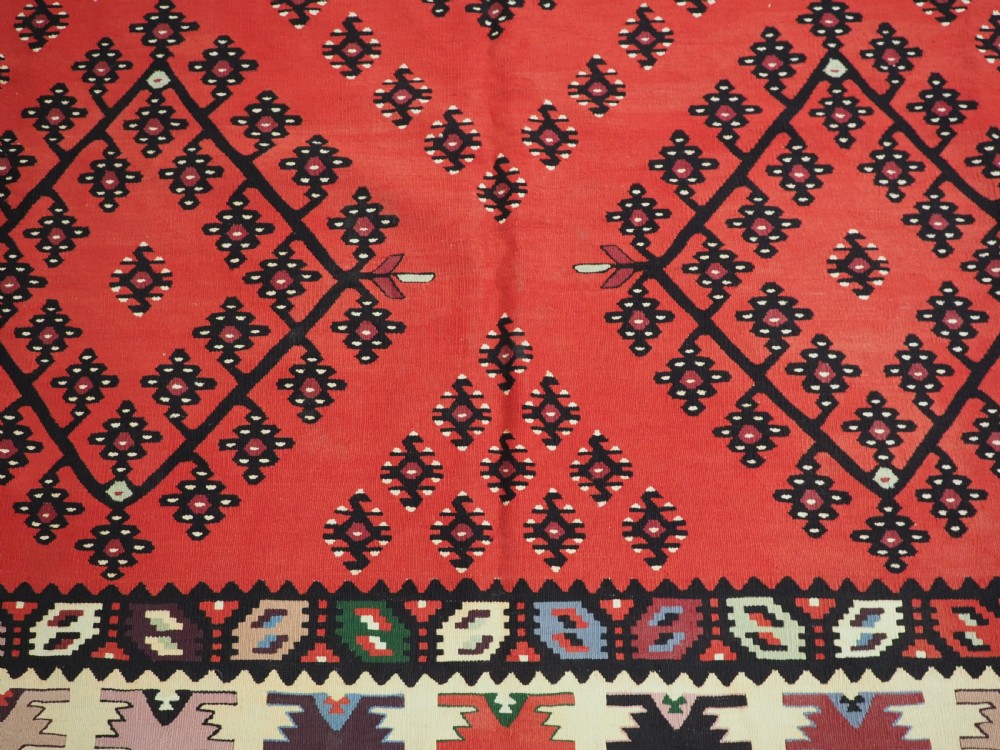An antique red flat-weave Pirot Sarkoy wool kilim featuring geometric diamond motifs and a multi-coloured decorative border. View X