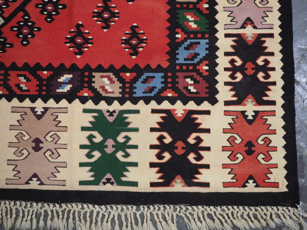 An antique red flat-weave Pirot Sarkoy wool kilim featuring geometric diamond motifs and a multi-coloured decorative border. View XI