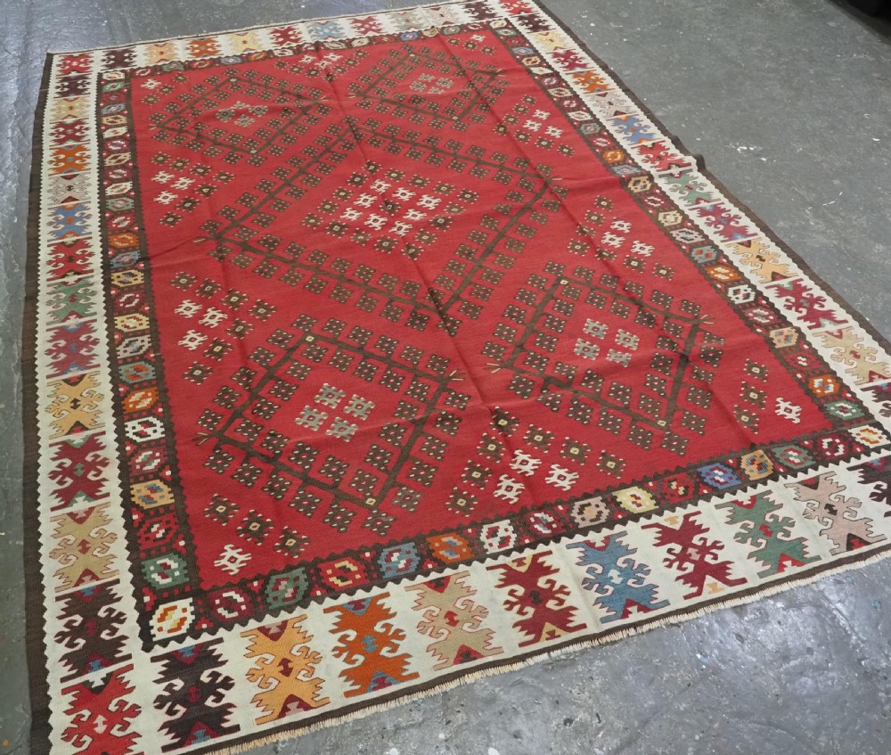 A red flatwoven antique Pirot Sarkoy kilim featuring geometric diamond motifs with intricate multi-coloured borders. View II