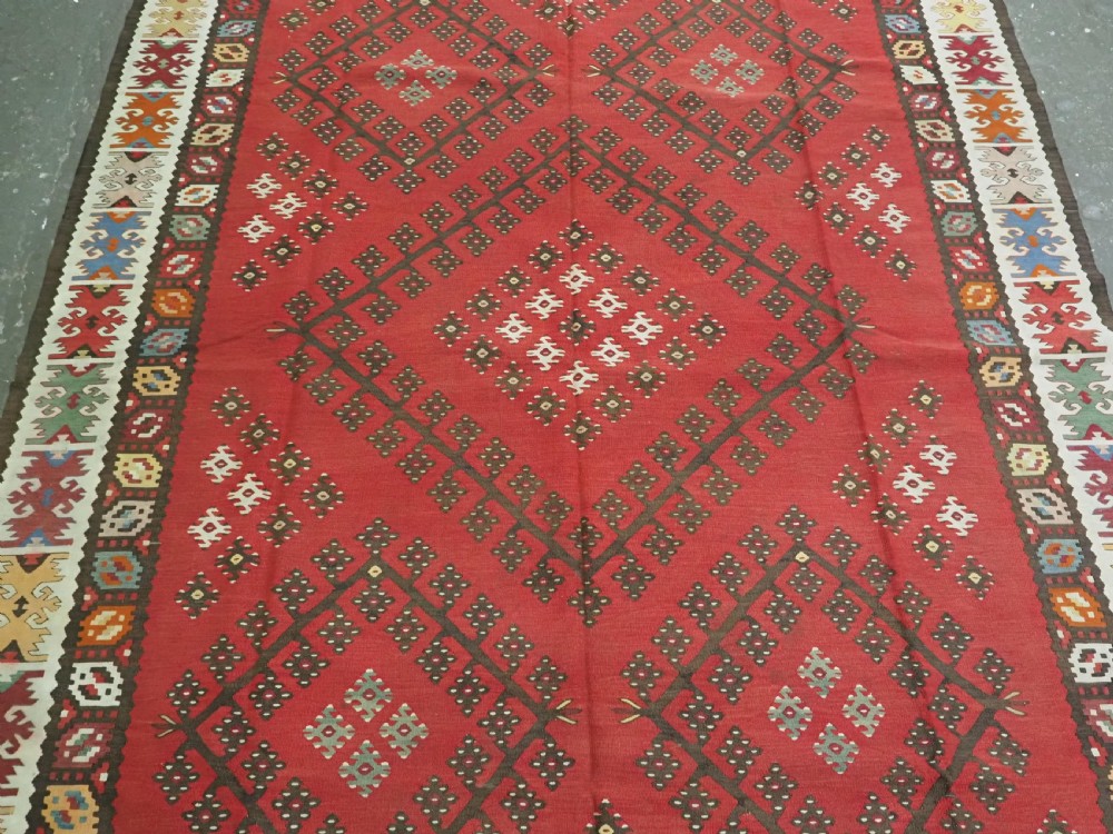 A red flatwoven antique Pirot Sarkoy kilim featuring geometric diamond motifs with intricate multi-coloured borders. View IV