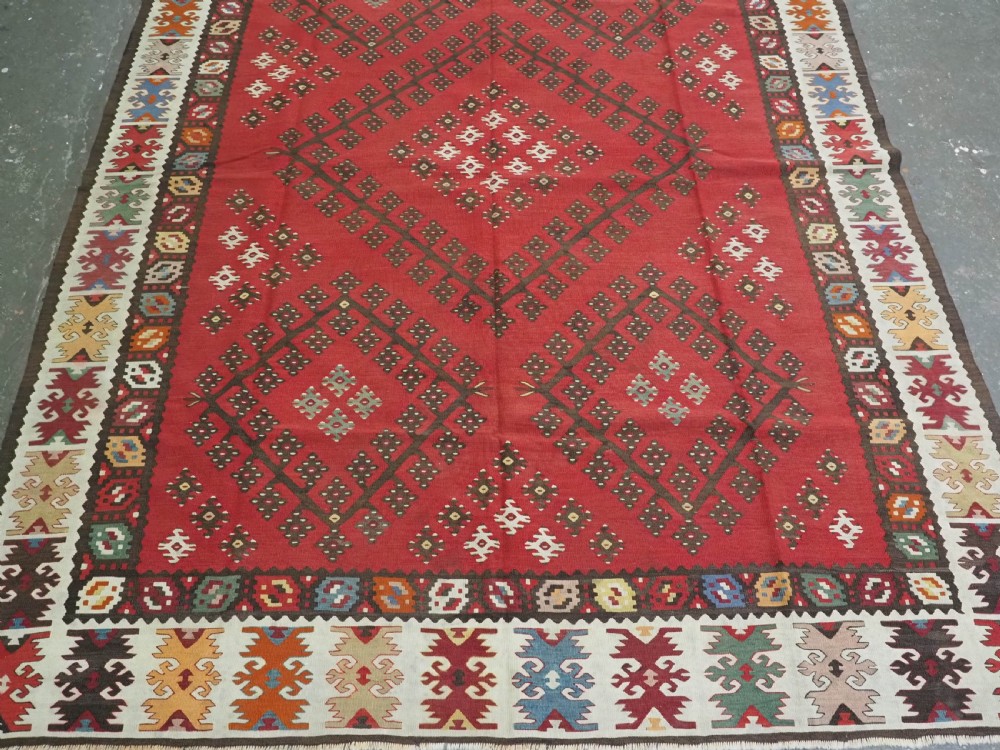 A red flatwoven antique Pirot Sarkoy kilim featuring geometric diamond motifs with intricate multi-coloured borders. View V