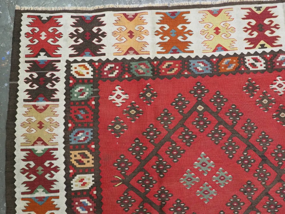 A red flatwoven antique Pirot Sarkoy kilim featuring geometric diamond motifs with intricate multi-coloured borders. View VI