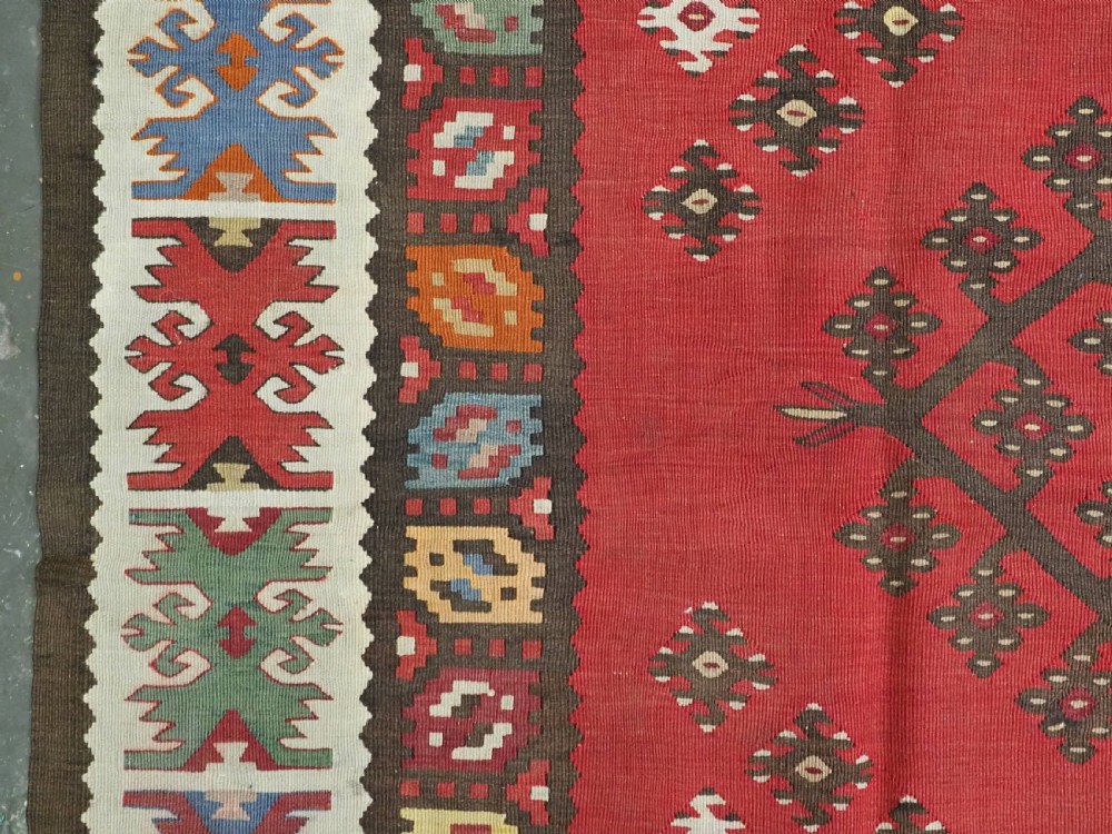 A red flatwoven antique Pirot Sarkoy kilim featuring geometric diamond motifs with intricate multi-coloured borders. View VII
