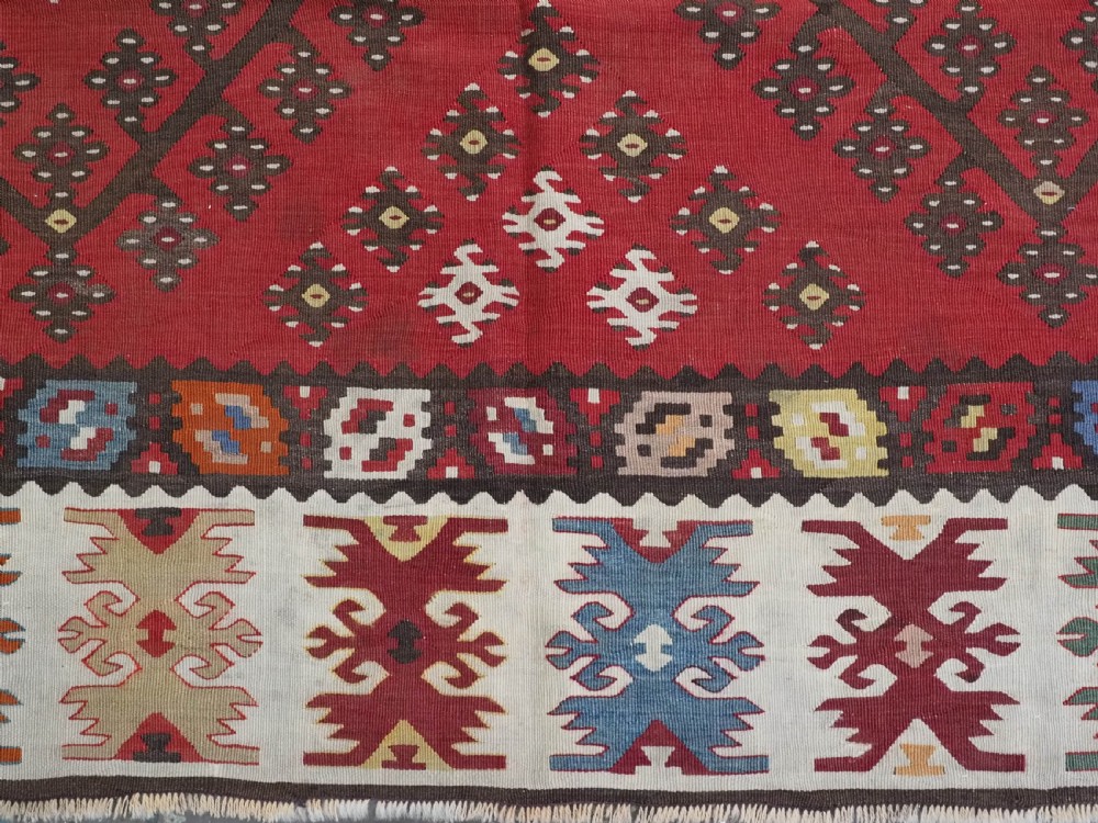 A red flatwoven antique Pirot Sarkoy kilim featuring geometric diamond motifs with intricate multi-coloured borders. View X