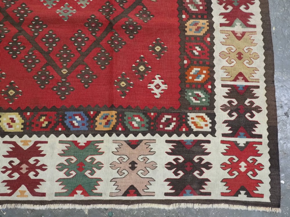 A red flatwoven antique Pirot Sarkoy kilim featuring geometric diamond motifs with intricate multi-coloured borders. View XI