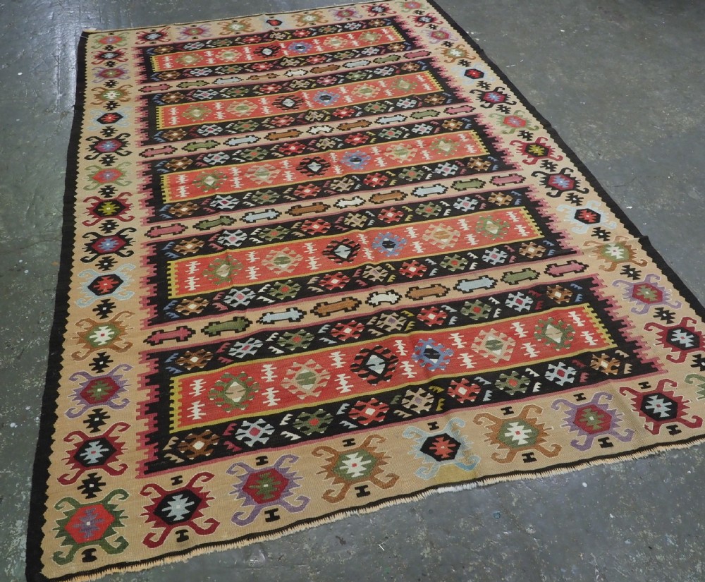A handwoven antique Pirot Sarkoy flatweave wool kilim rug featuring horizontal bands of geometric motifs in terracotta, beige, yellow, green, and dark brown. View II