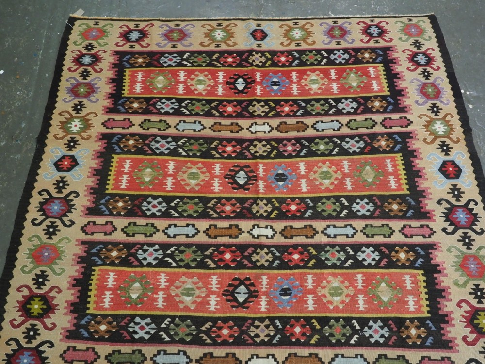 A handwoven antique Pirot Sarkoy flatweave wool kilim rug featuring horizontal bands of geometric motifs in terracotta, beige, yellow, green, and dark brown. View III