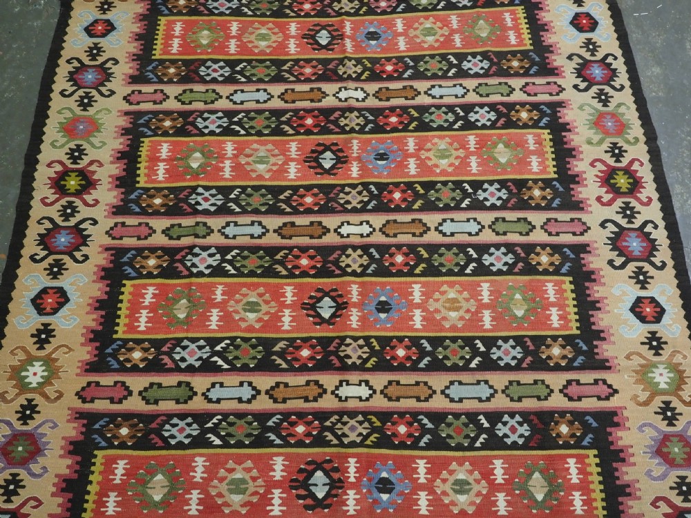 A handwoven antique Pirot Sarkoy flatweave wool kilim rug featuring horizontal bands of geometric motifs in terracotta, beige, yellow, green, and dark brown. View IV
