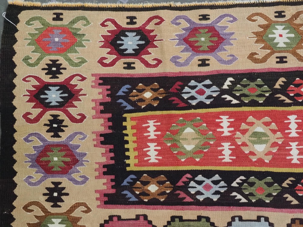 A handwoven antique Pirot Sarkoy flatweave wool kilim rug featuring horizontal bands of geometric motifs in terracotta, beige, yellow, green, and dark brown. View VI