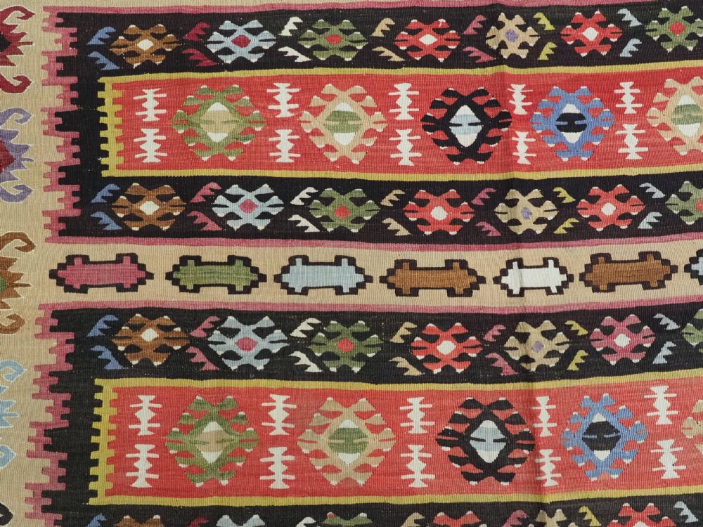 A handwoven antique Pirot Sarkoy flatweave wool kilim rug featuring horizontal bands of geometric motifs in terracotta, beige, yellow, green, and dark brown. View VIII