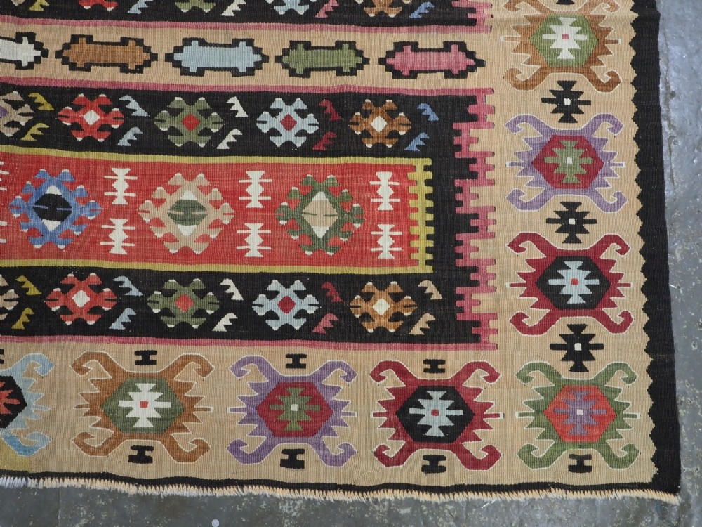 A handwoven antique Pirot Sarkoy flatweave wool kilim rug featuring horizontal bands of geometric motifs in terracotta, beige, yellow, green, and dark brown. View X