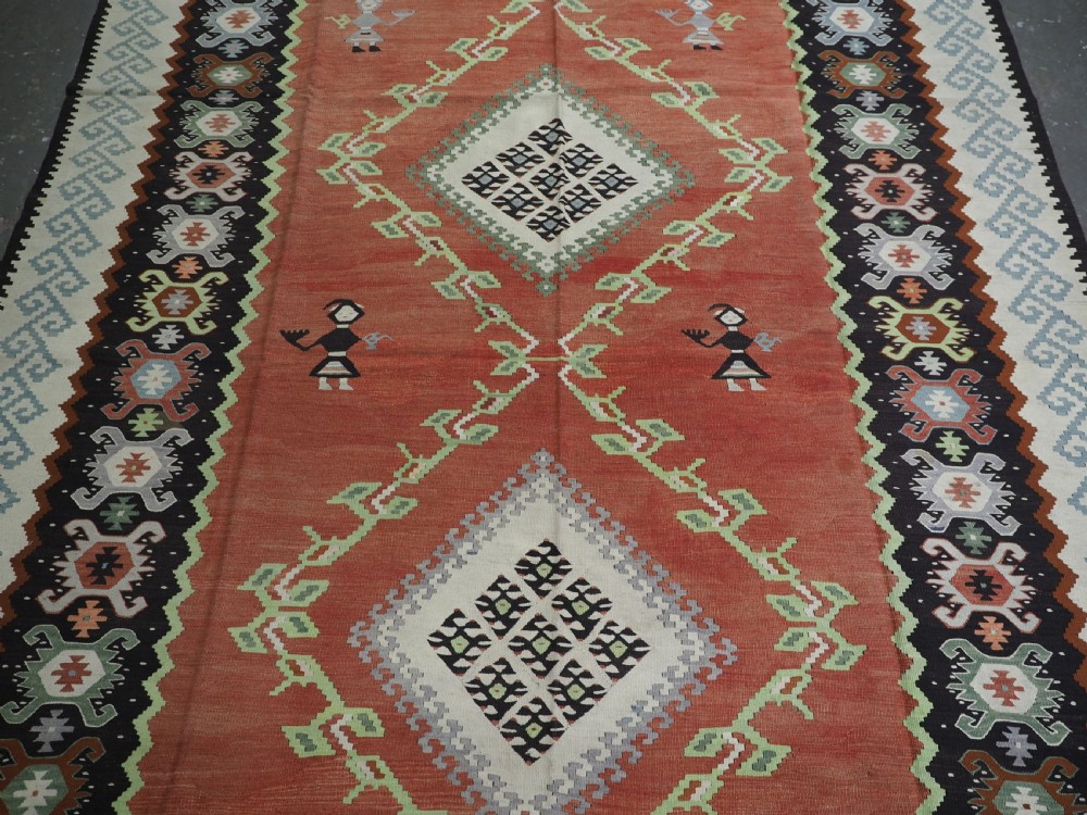 An antique woven wool Pirot Sarkoy kilim rug featuring a central terracotta red field decorated with diamond medallions and intricate geometric borders. View IV