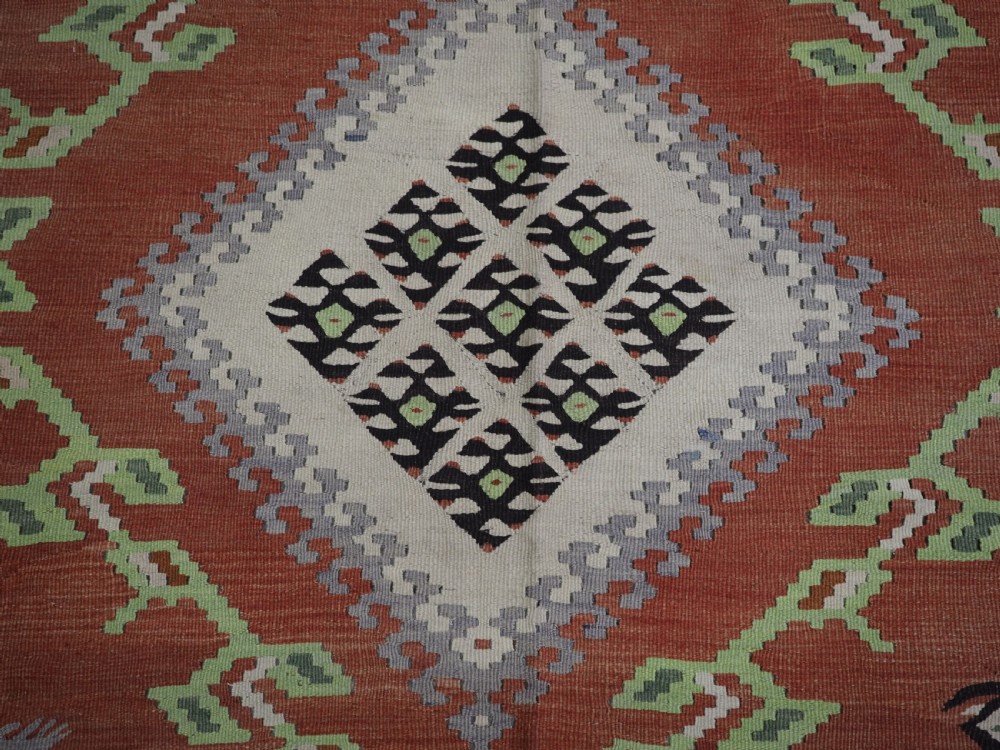 An antique woven wool Pirot Sarkoy kilim rug featuring a central terracotta red field decorated with diamond medallions and intricate geometric borders. View XII