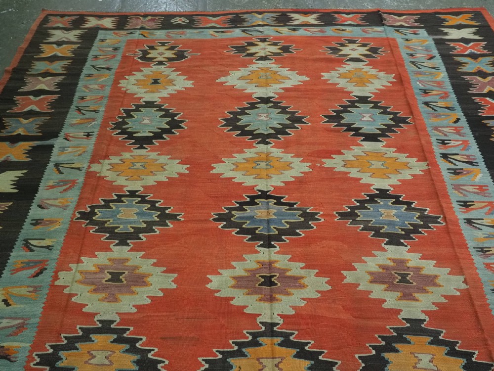 A large antique Pirot Sarkoy flat-weave wool kilim carpet featuring repeating diamond medallions on a terracotta field with dark geometric borders. View III