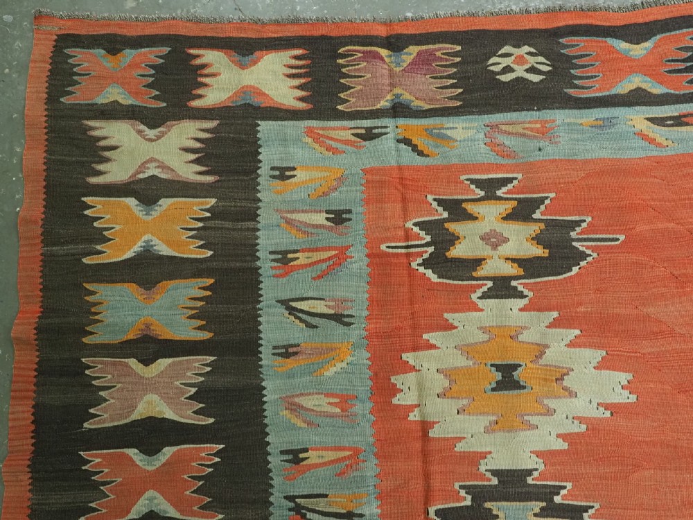 A large antique Pirot Sarkoy flat-weave wool kilim carpet featuring repeating diamond medallions on a terracotta field with dark geometric borders. View VII