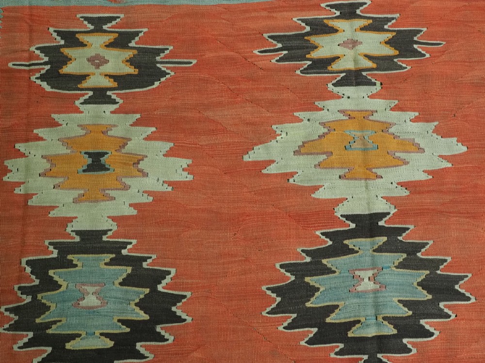 A large antique Pirot Sarkoy flat-weave wool kilim carpet featuring repeating diamond medallions on a terracotta field with dark geometric borders. View VIII