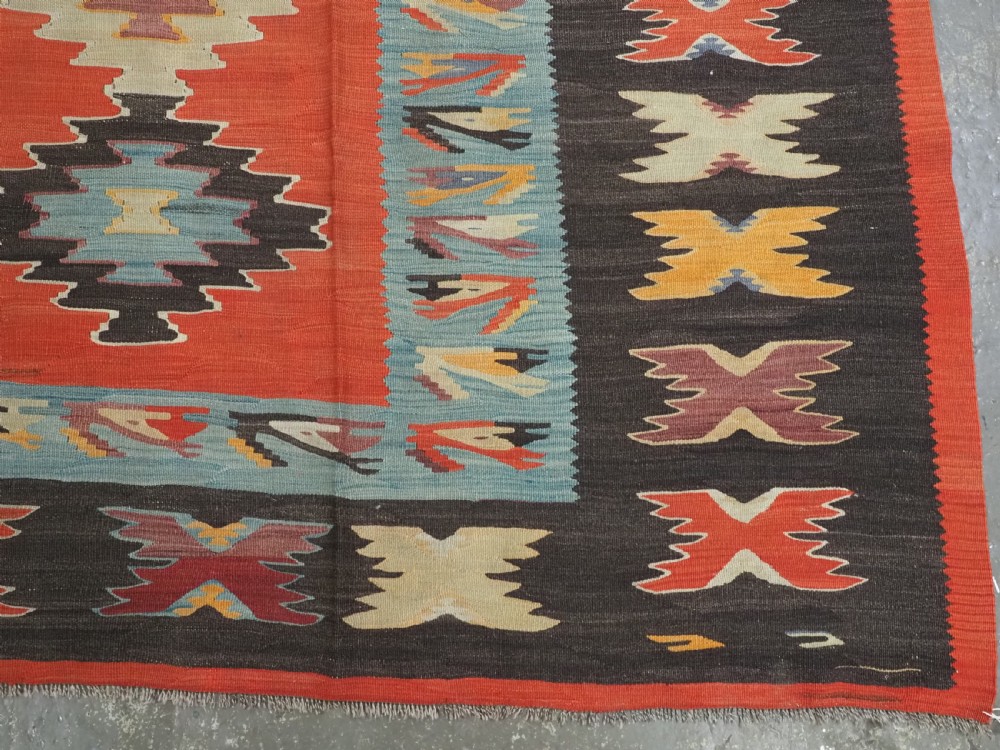 A large antique Pirot Sarkoy flat-weave wool kilim carpet featuring repeating diamond medallions on a terracotta field with dark geometric borders. View XI