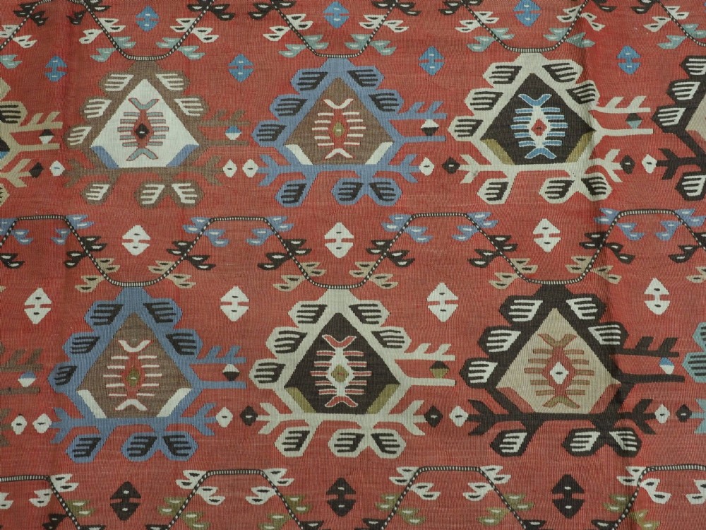 An antique handwoven wool kilim rug featuring a terracotta central field with geometric repeat motifs and patterned borders. View VIII