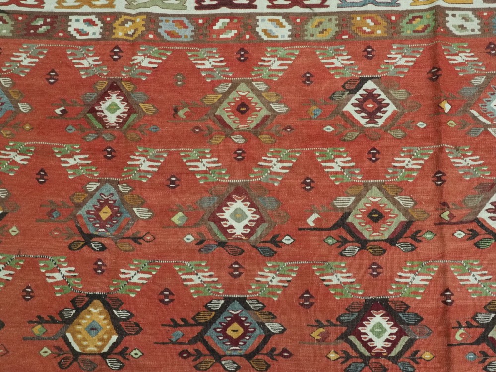 A large antique Pirot Sarkoy flatweave wool kilim rug featuring repeating geometric diamond motifs on a terracotta red field with decorative patterned borders. View VIII