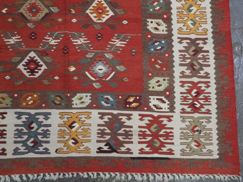 A large antique Pirot Sarkoy flatweave wool kilim rug featuring repeating geometric diamond motifs on a terracotta red field with decorative patterned borders. View XI