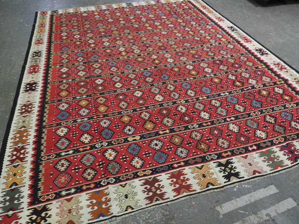 A large antique red flatweave wool kilim rug featuring horizontal bands filled with geometric diamond patterns and detailed multicoloured borders. View II
