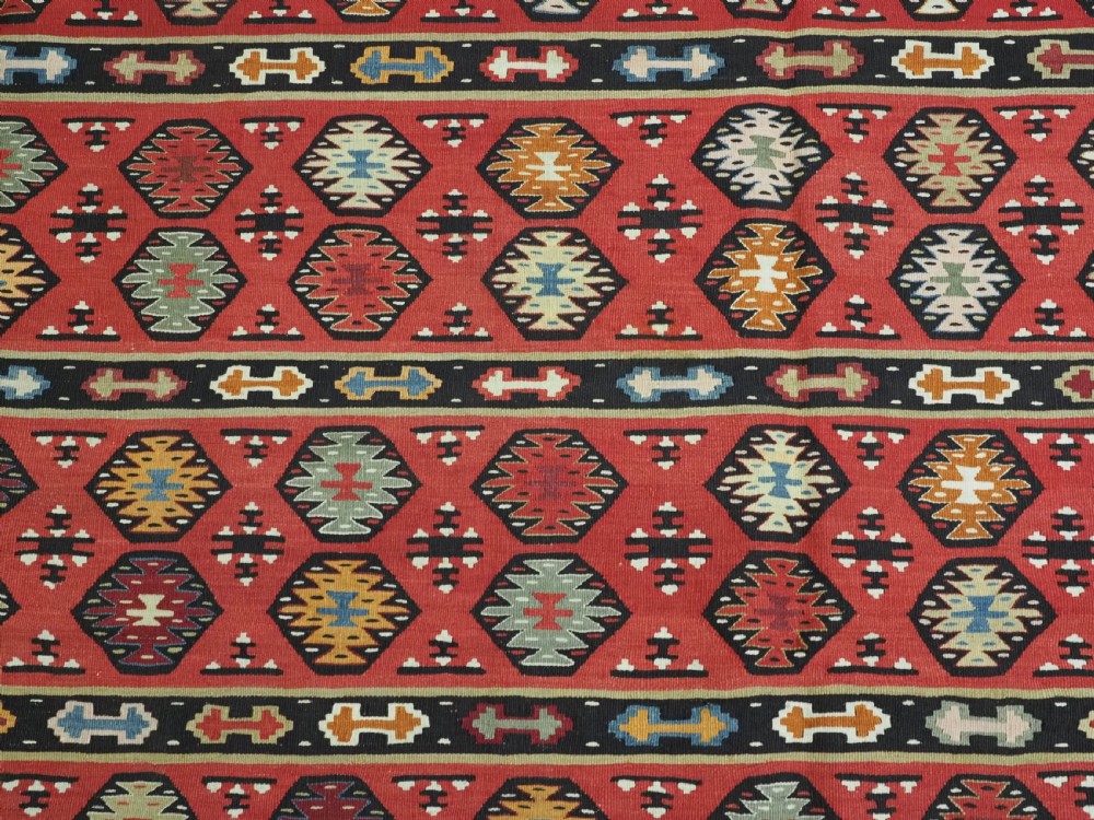 A large antique red flatweave wool kilim rug featuring horizontal bands filled with geometric diamond patterns and detailed multicoloured borders. View IX