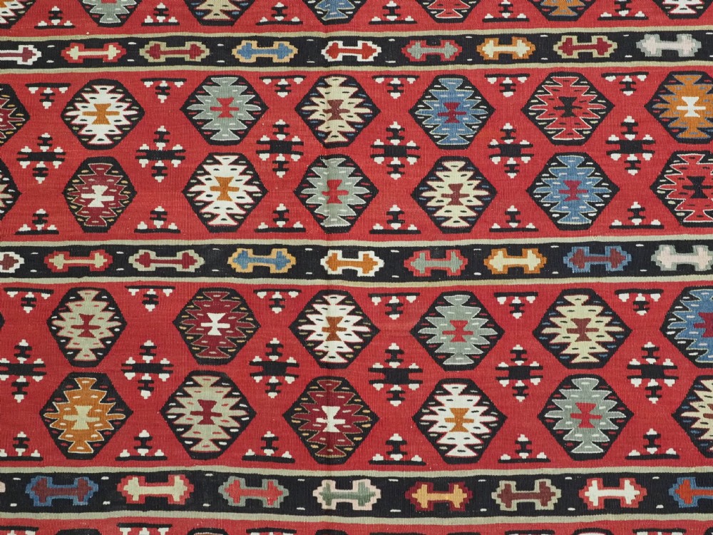 A large antique red flatweave wool kilim rug featuring horizontal bands filled with geometric diamond patterns and detailed multicoloured borders. View X
