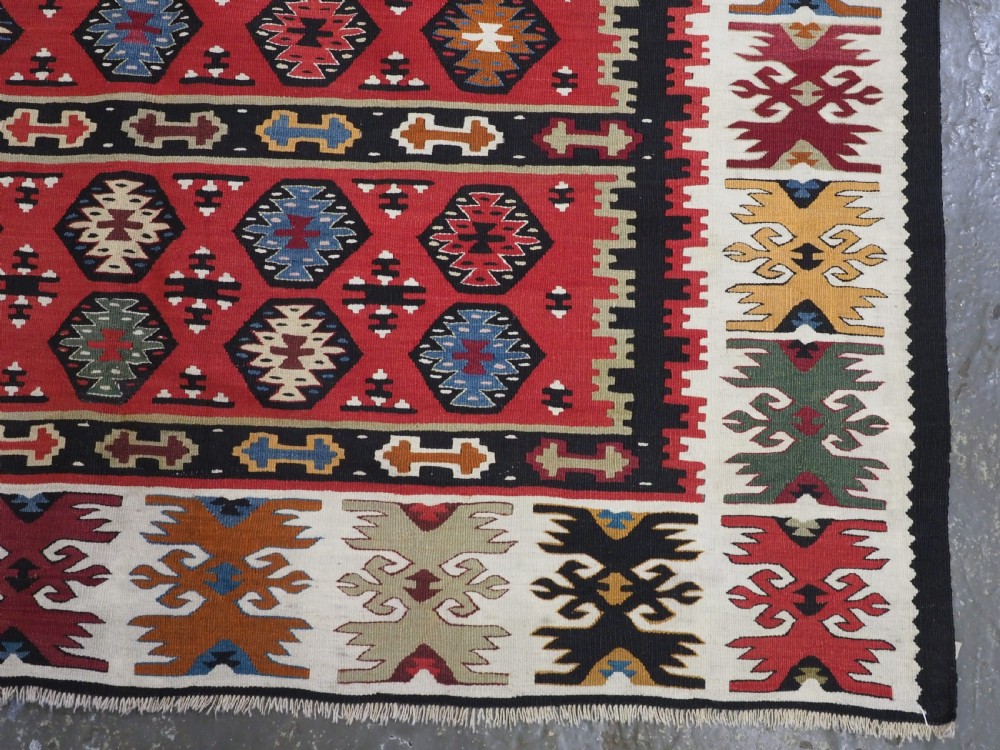 A large antique red flatweave wool kilim rug featuring horizontal bands filled with geometric diamond patterns and detailed multicoloured borders. View XI