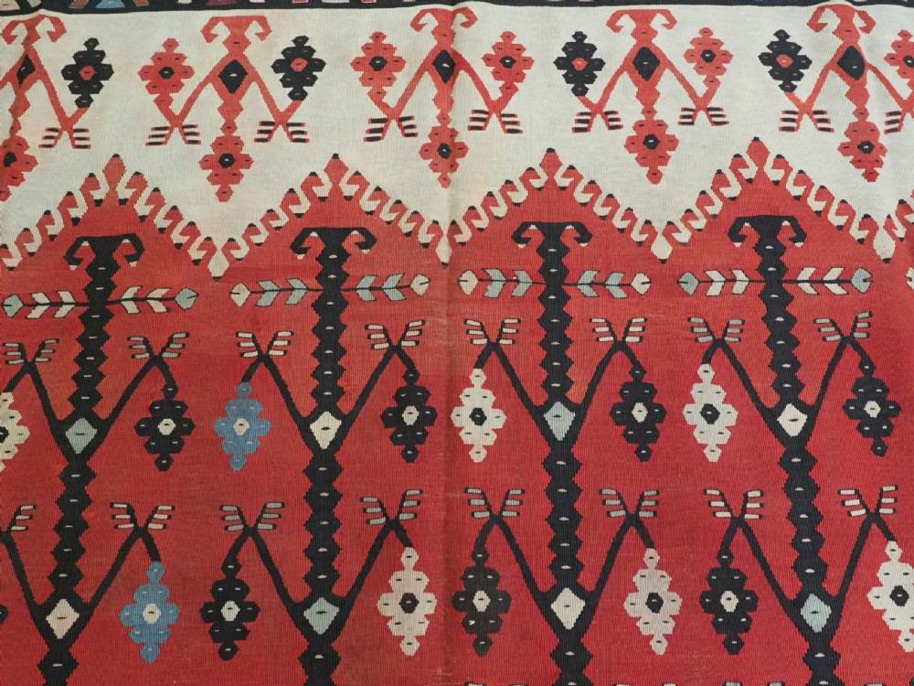 An antique flatweave wool kilim carpet featuring a central red field patterned with vertical flowering tree motifs surrounded by layered geometric borders. View VIII