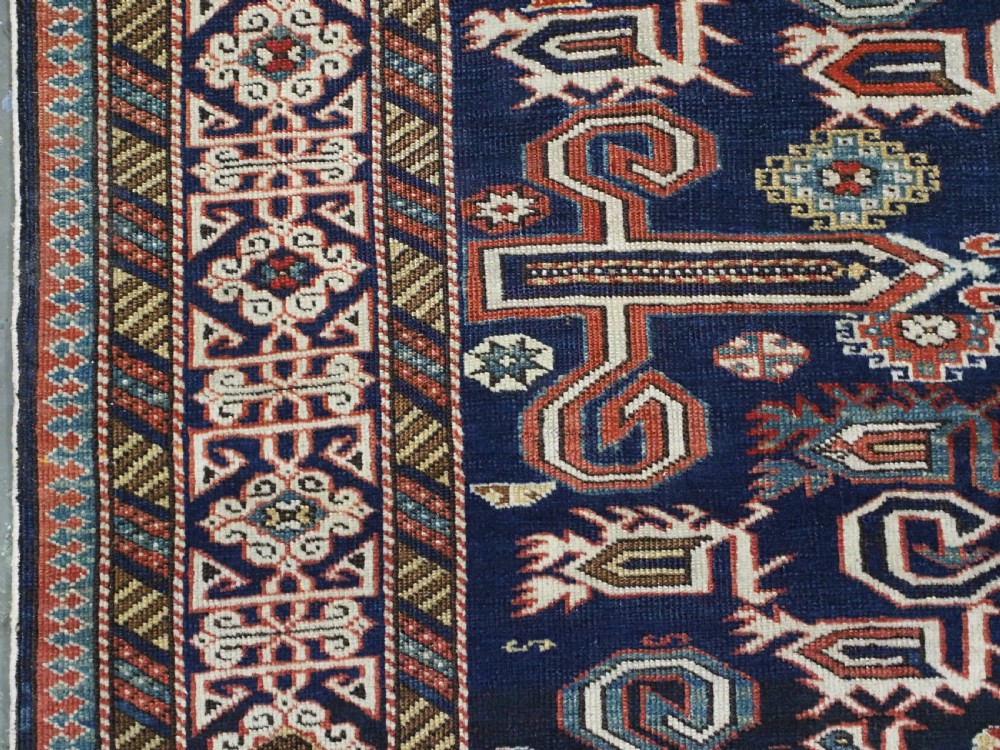 An antique hand-knotted Caucasian Perepedil rug featuring a navy blue field with geometric rams horn motifs and star medallions framed by multi-layered geometric borders. View VI
