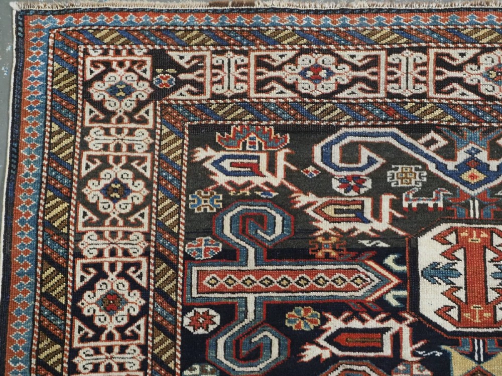 An antique hand-knotted Caucasian Perepedil rug featuring a navy blue field with geometric rams horn motifs and star medallions framed by multi-layered geometric borders. View VII